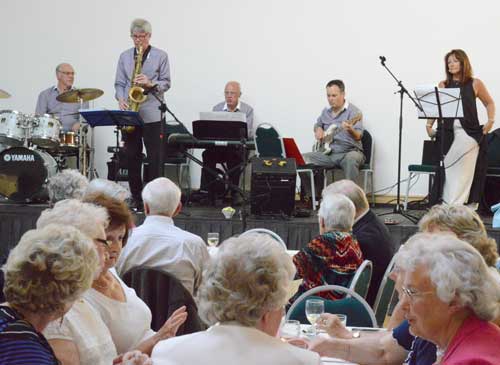 Image of the Sue Caplin band playing watched by attendees.
