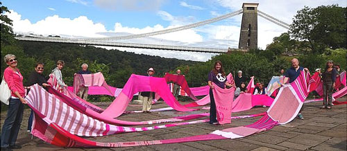 Image of a long pink scarf in front of the suspension bridge.